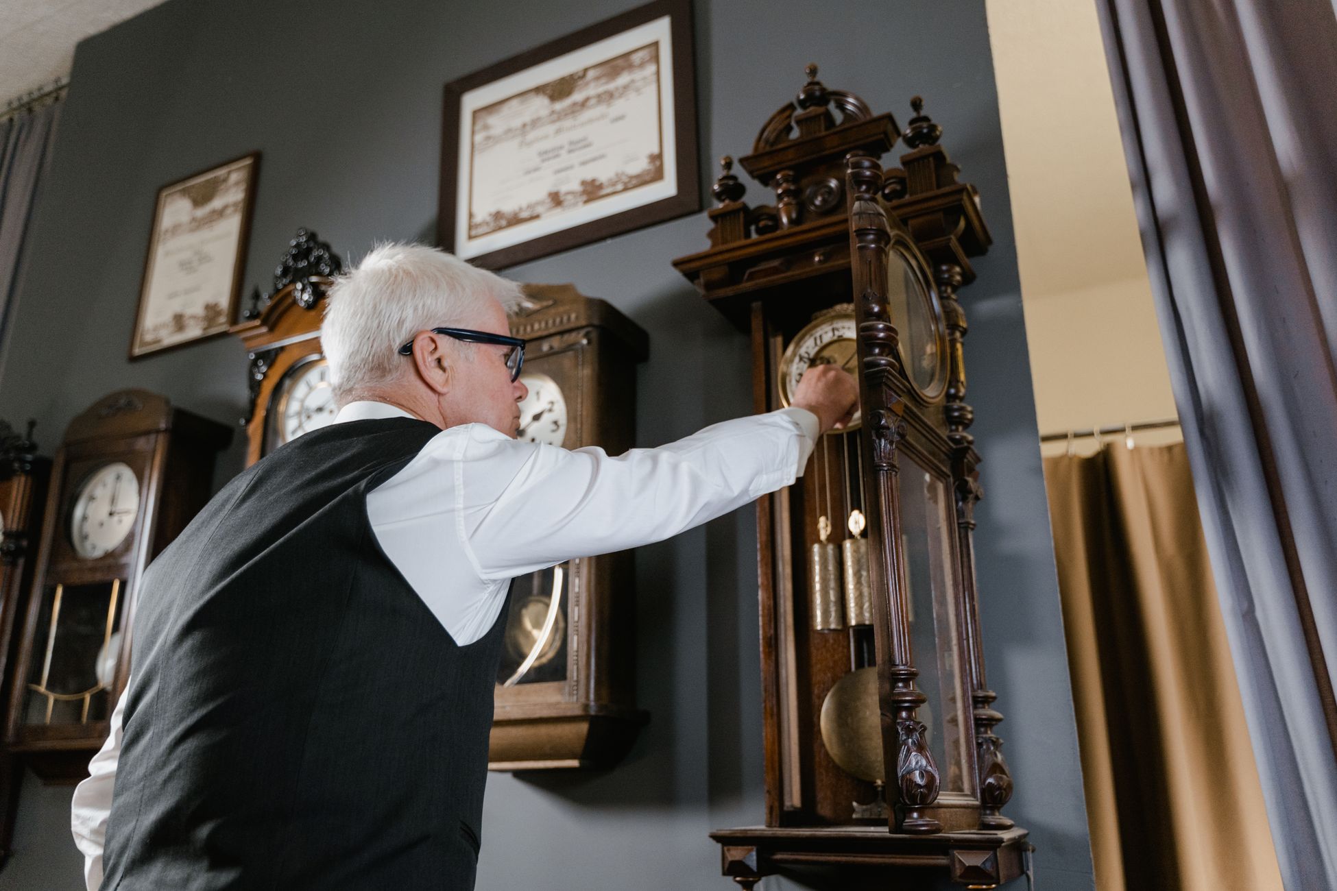 Clockmaker adjusting a grandfather clock on site